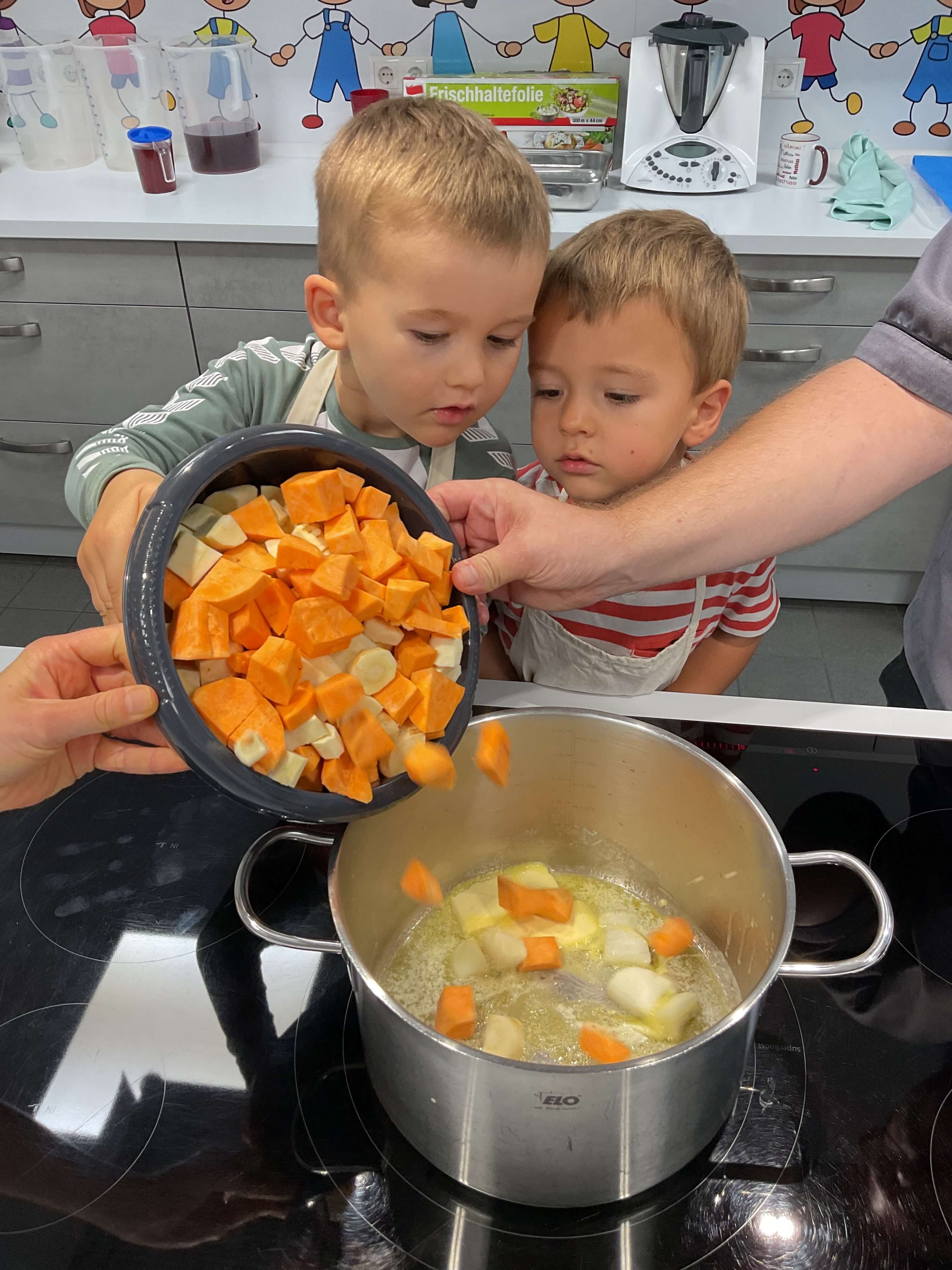 Kinder schütten gewürfelten Kürbis in einen Topf